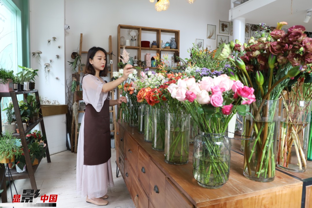 王黎媛是一名河南姑娘，在昆明念完大學(xué)后，就再也舍不下春城的藍(lán)天陽光、青山碧水，更舍不下這里的四時繁花，于是就干脆留了下來，成了一名媒體人。2017年的時候又毅然辭去工作，創(chuàng)業(yè)開起了花店，成了都市里的一名“花房姑娘”。圖為王黎媛在自己的花店中整理鮮花。新華網(wǎng) 周亞平/攝 念新洪/文